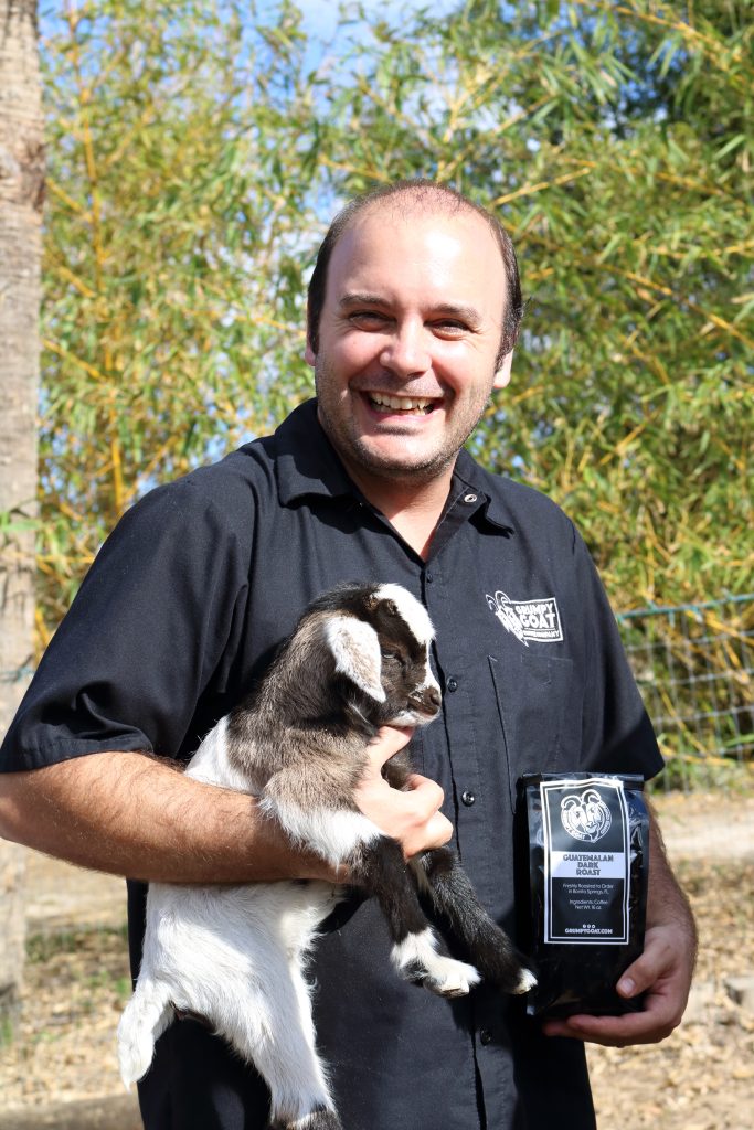 Brian Abernathy, founder and master roaster of Grumpy Goat Coffee holding a goat